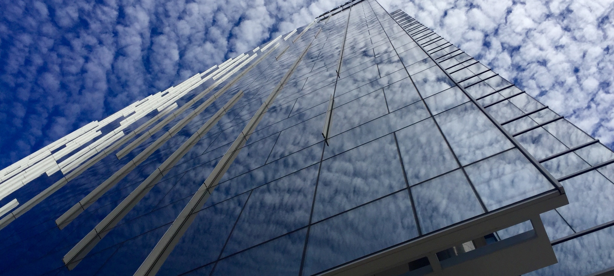 Side of KPMG Plaza building with view of clouds.